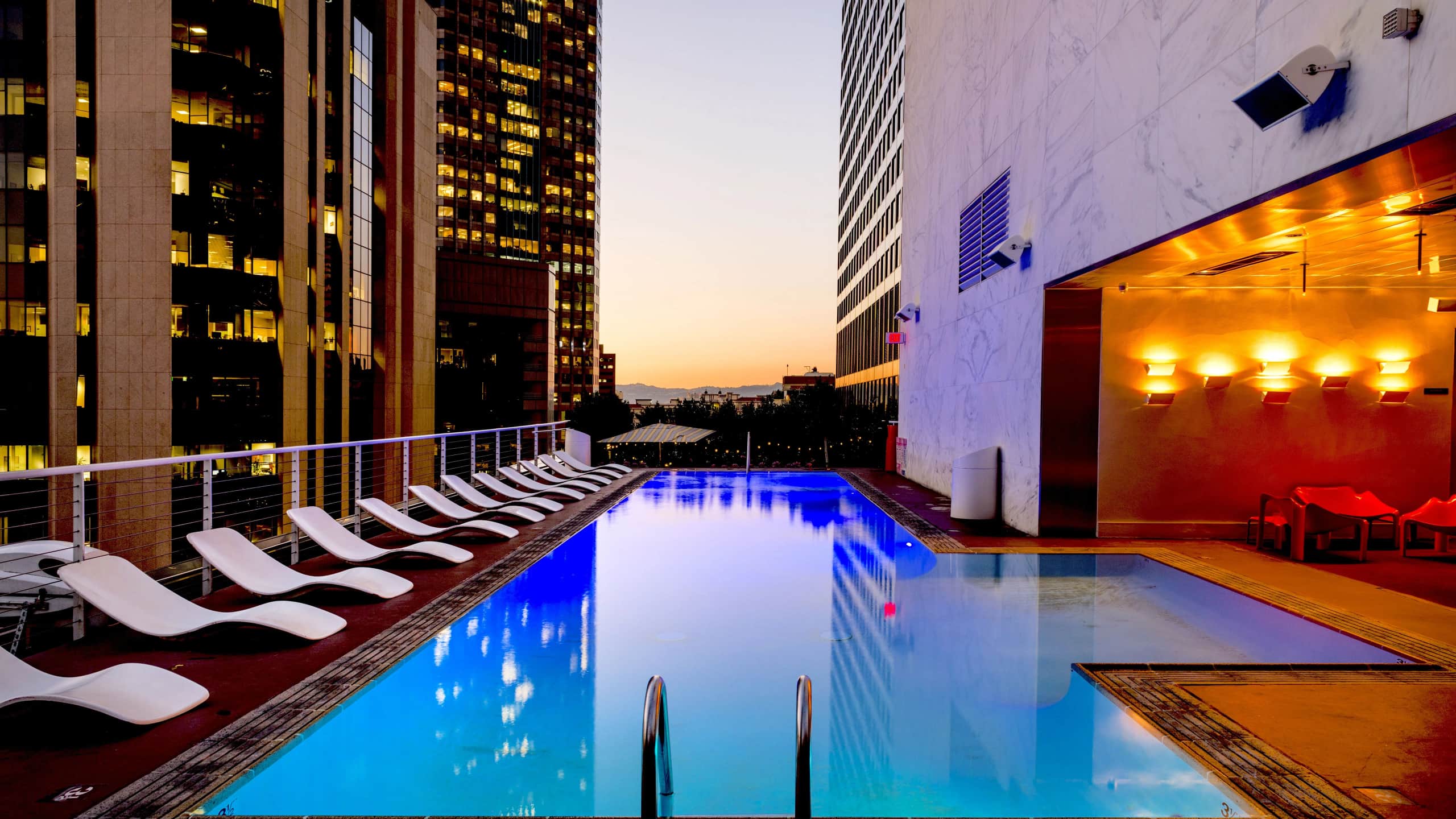 Rooftop infinity pool overlooking a city skyline at blue hour
